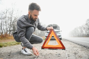 Sad man near broken car searching help in field