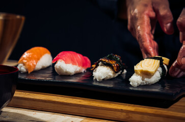 Japanese chef making rice nigiri sushi with tuna, salmon, shrimp,traditional Japanese food ,Dark Tone