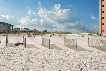 Fototapeta na wymiar Destin, Florida- Wood fence panels in a row on a beach white sand against the sky