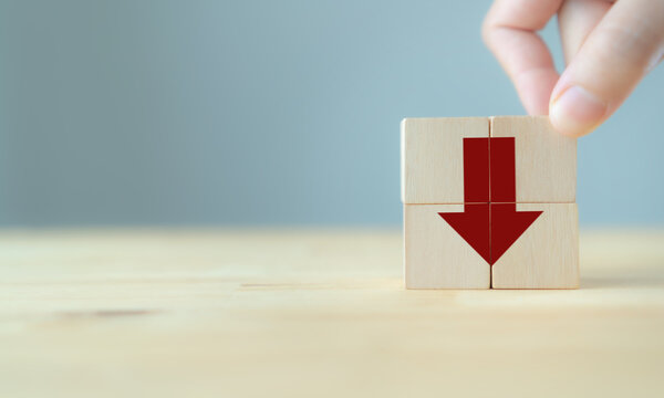 Red arrow points down sign on wooden cube blocks and copy space. .Reduction concept, financial, investment, recession crisis, interest rate decline, risk management, cost, price and carbon emissions.