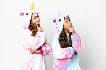 Friends girls with unicorn pajamas over isolated white background thinking an idea while looking up