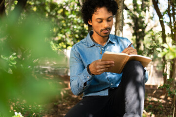 focused man writing in journal ideas and enjoying nature in the park
