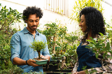happy horticulturist explaining to client about bonsai at plant nursery