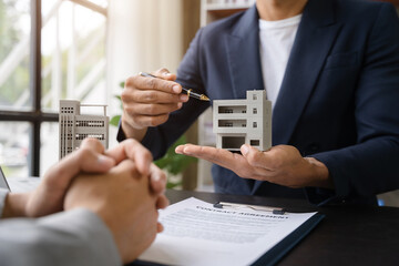 Buying a home or insurance deal, an insurance agent pointing a pen to those interested in renting a...