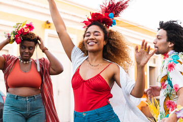 Fun mixed race woman dancing Carnival in the street. Brazilian people enjoying Carnaval festival in...