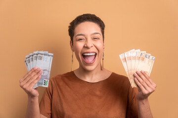 cheerful afro brazilian woman celebrating successful business money in all beige colors. financial,...