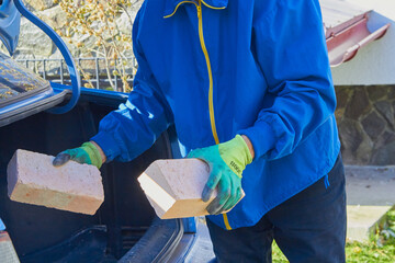 brick in the hands of a builder,a man unloads bricks in two hands, delivery of bricks