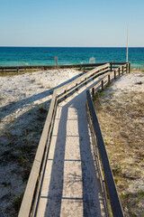 Top view of a board walk over the white sand with grass heading to the beach at Destin, Florida
