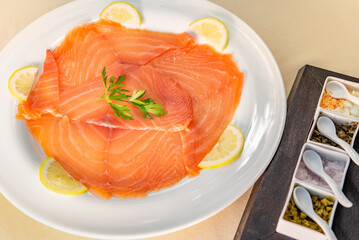 Smoked salmon carpaccio with garnish served on a white plate