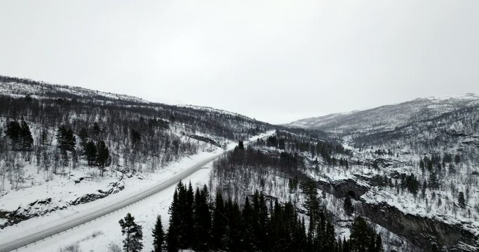 European E8 route crossing snowy rural landscape, northern Norway. Aerial drone panoramic view. Sky for copy space
