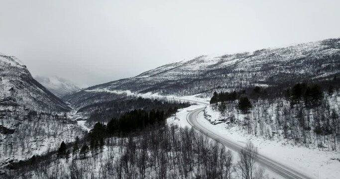 Aerial along Highway E8 through white snow covered winter landscape, Norway