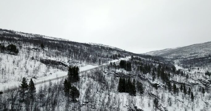 Isolated car driving on winter iced road in Norway. Aerial drone panoramic view. Sky for copy space