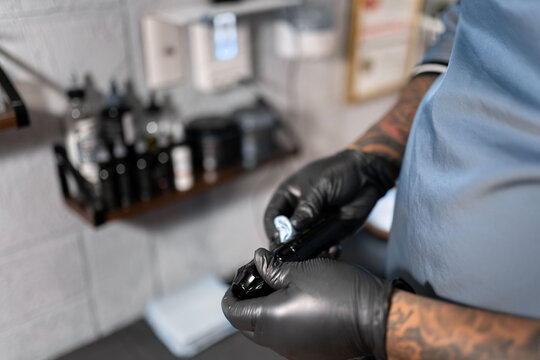 A tattoo artist is cleaning his tattoo machine