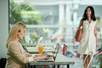 Female digital nomad working on laptop in cafe