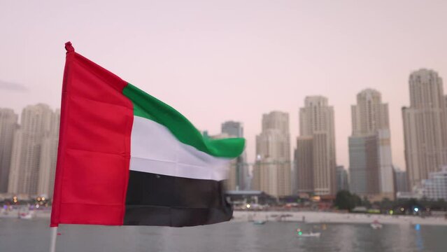 United Arab Emirates flag with the Dubai Marina skyline in the background