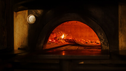 In Restaurant Professional Chef Uses Pizza Peel to Turn Pizza in the Wood Fire Stone Oven. Traditional Italian Cooking Family Recipe. Authentic Pizzeria, Delicious Organic Food. Front View No People