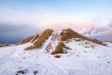 Fototapeta na wymiar Snow covered dune with beautiful colorful cloudy skies in the background