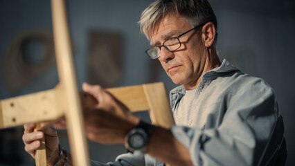 Close Up of a Carpenter Putting on Glasses, Looking at a Blueprint and Starting to Assemble a...