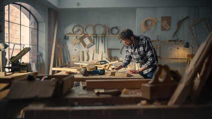 Fototapeta na wymiar Wide Shot of an Artisan Furniture Designer Reading Blueprint and Starting to Assemble Legs of a Wooden Chair. Stylish Carpenter Working in a Studio in Loft Space with Tools on the Walls.