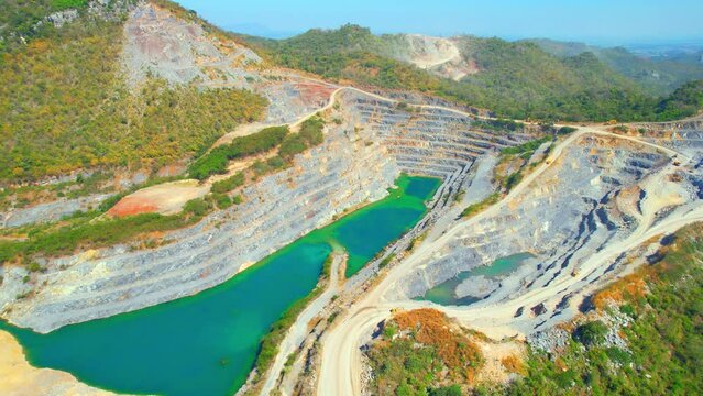 Aerial view from a drone flying over a quarry and turquoise pond in the tropics. Southeast asia. Commercial stone industry. Health and respiratory problems. Construction concept. 4k Footage