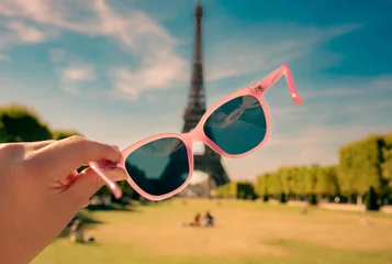 Zelfklevend Fotobehang Paris - pink sunglasses in a tourist hand. Eiffel Tower as background - travel poster. © pinkyone