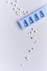 Tablet, pill dispenser and tablets. Flat lay, top view on off white backgrund. Blue round daily...