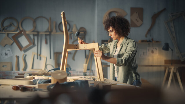 Young Woodworker Checking the Layout Manual of a Stylish Handmade Wooden Chair. Talented Female Furniture Designer Working in a Workshop in a Creative Loft Space with Tools and Equipment. - Powered by Adobe