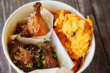 caramelized chicken with sesame and garlic, meat strips in paper bucket 