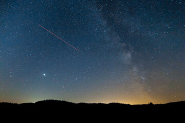 milky way starascape with jupiter and plane light trail