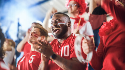 Fototapeta Sport Stadium Soccer Match: Diverse Crowd of Fans Cheer for their Red Team to Win. People Celebrate Scoring a Goal, Championship Victory. Group People with Painted Faces Cheer, Shout, Have Fun obraz