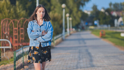 A lonely girl walks along the city's promenade.