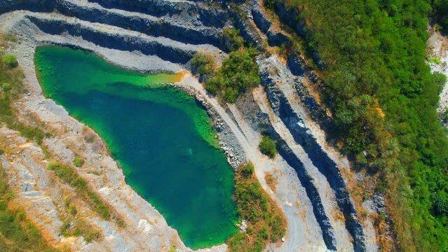Drones are flying over quarry and turquoise pond. commercial stone industry. Construction and respiratory pollution concept. environmental issues. Southeast asia. Aerial view footage. 4K
