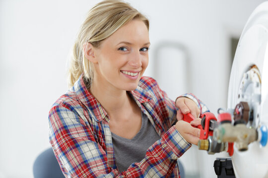 portrait of female plumber working on boiler