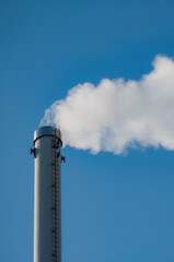 Factory chimney with smoke. Industrial pipe. Blue sky at sunny day. Air pollution/