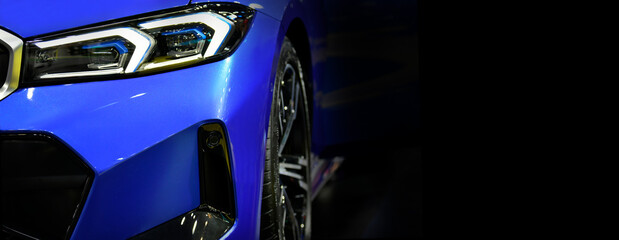 Front headlights of blue modern car on black background,copy space