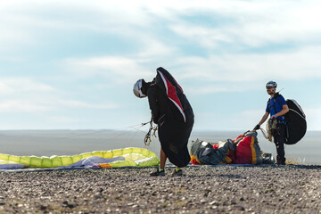Two paragliders getting ready for taking off above the hill.