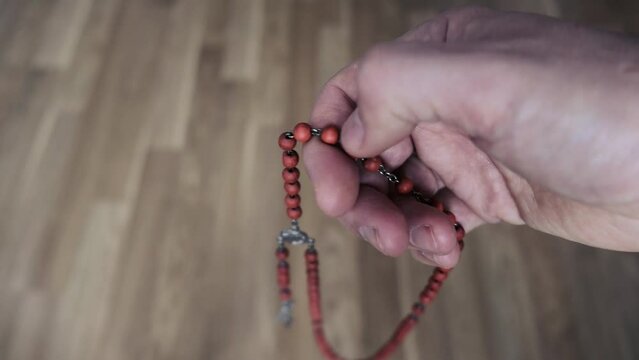 Close-up, a man's hand sorts through beads during prayer. Shot in 4k resolution.