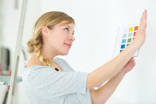 woman next to a wall looking to color samples