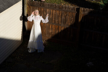 fashion portrait of non-binary person wearing white dress in dramatic sunlight