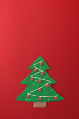 Gingerbread Christmas tree shaped cookie made by hand with plasticine, on a red gradient background with copy space. Christmas and happy new year greeting card concept