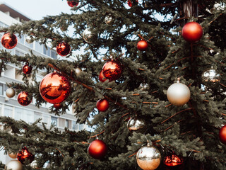 Closeup of festively decorated outdoor christmas tree with bright red and beige balls