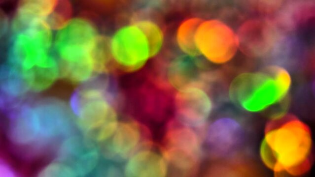 Spinning bright and shiny multicolored bokeh spots background, turning clockwise and sparkling in light reflections.