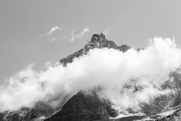 Black and white photo of Aiguille du Midi between clouds at French Alps.