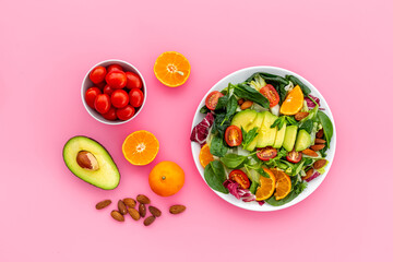 Fresh green salad with avocado and tomatoes, top view