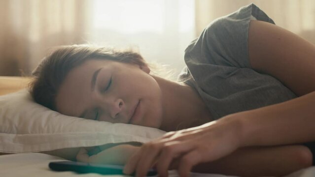 Caucasian woman turn off the alarm clock and waking up at morning. Shot with RED helium camera in 8K. 