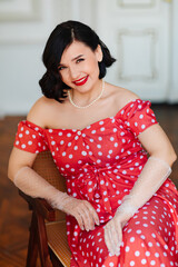 portrait of beautiful and happy brunette in red retro dress and gloved 