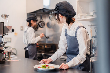 Fototapeta na wymiar レストランのキッチンで働く2人の女性スタッフ