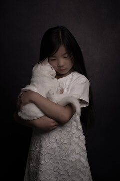 dark painterly portrait of a girl in white dress holding her cat close