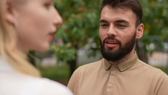 Close-up of cheerful young couple lovers married family standing closeness together in summer park on romantic date. Bearded happy man talking with unrecognizable caring girlfriend outdoors.