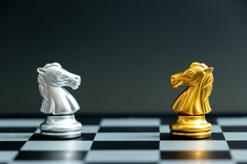 Gold horse knight in chess game face with the another silver knight on black background (Concept for company strategy, business victory or decision)